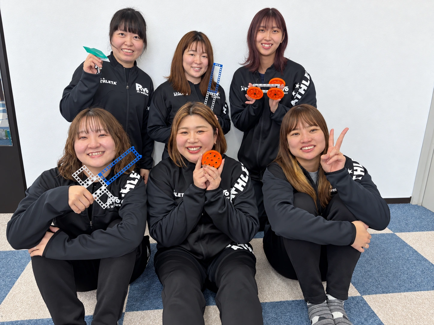 教材を手に笑顔で集まる6人のスタッフ